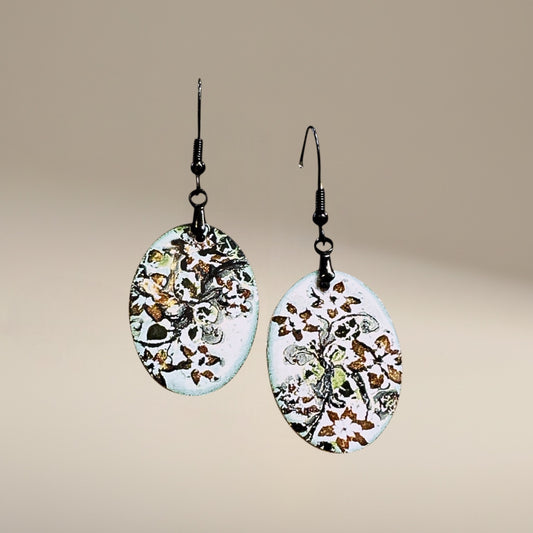 Bedrock Rose hand-enameled oval dangle earrings with white base and black floral motif. Copper earrings with glass-like finish.
