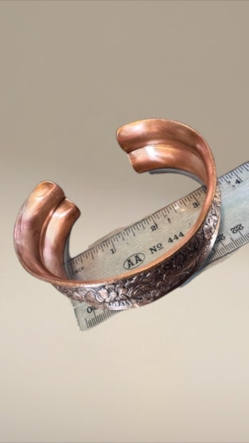 Bedrock Rose extra-large copper cuff with a double curve and detailed floral pattern and antiqued finish.