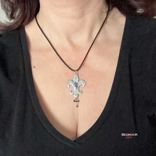 Bedrock Rose sterling silver fleur-de-lis pendant with a blue marquis gemstone on a black cord necklace