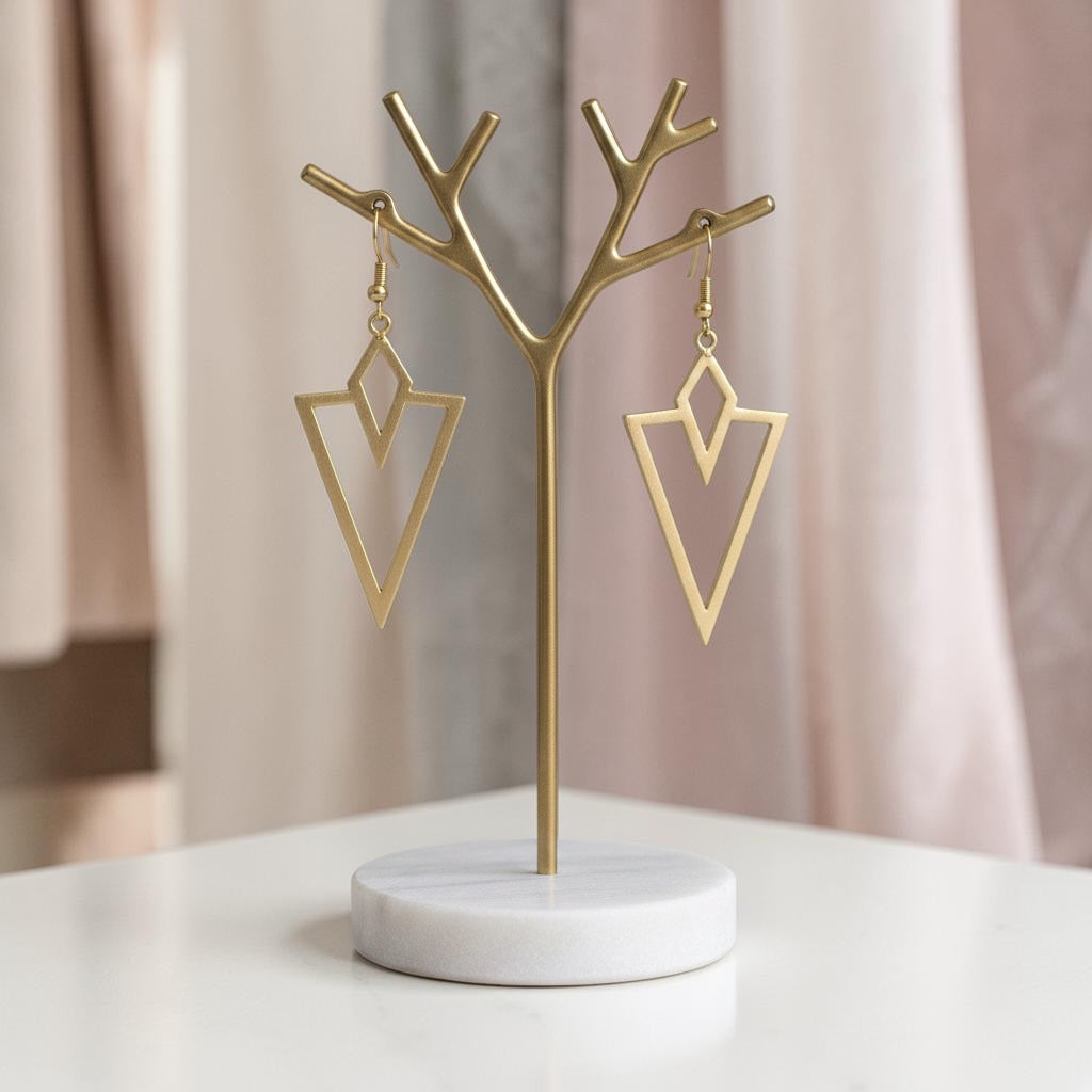 Bedrock Rose gold arrowhead dangling earrings with geometric laser-cut design on a gold display stand.