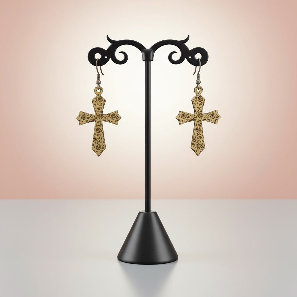 Bedrock Rose gold cross dangle earrings featuring intricate laser-etched floral rose patterns on a display stand.