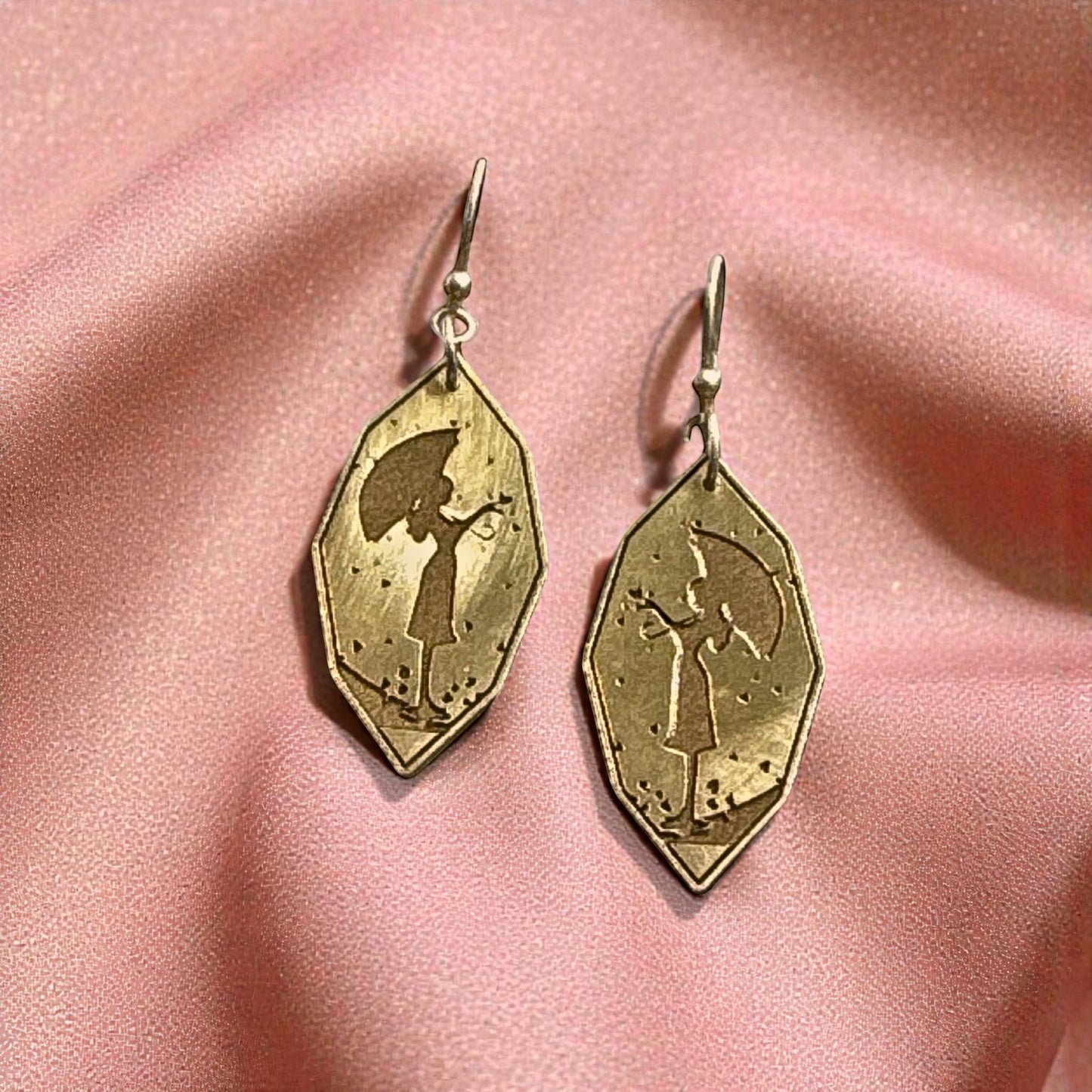 Bedrock Rose gold-plated dangle earrings featuring a silhouette of a girl holding an umbrella.