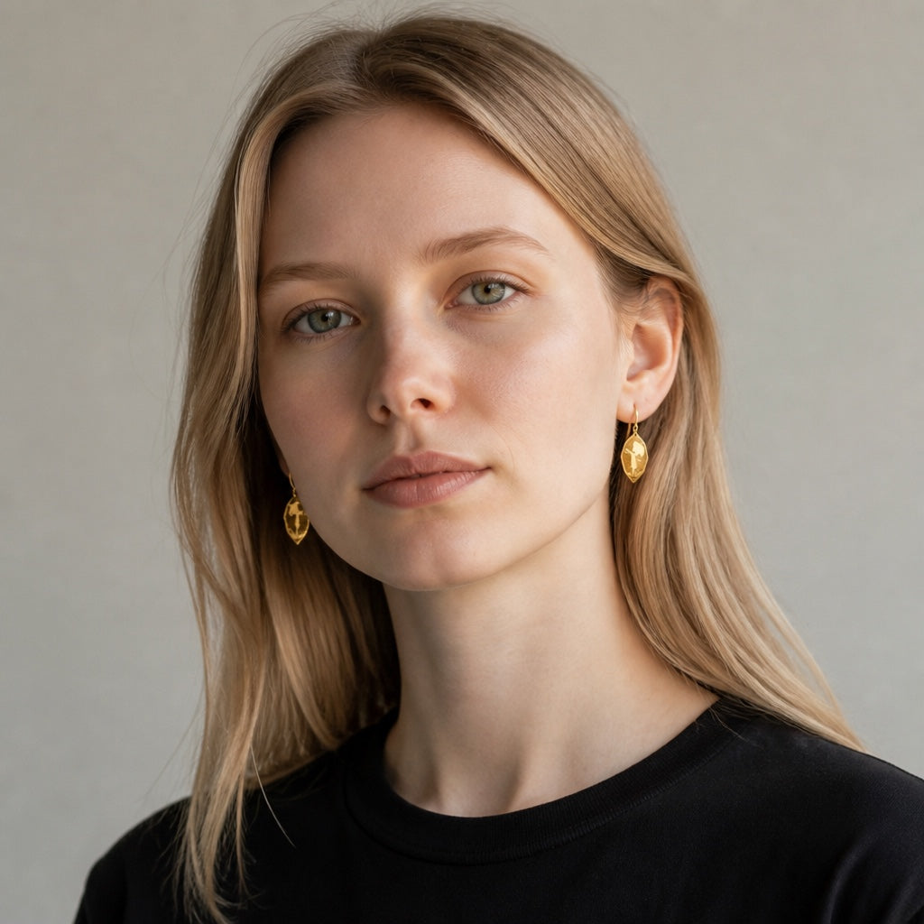 Bedrock Rose gold-tone earrings featuring a girl with an umbrella silhouette worn by a woman with blonde hair.