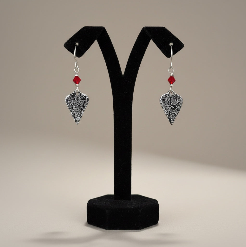 Bedrock Rose sterling silver dangle earrings with roll-printed grape leaf pattern and ruby red crystal accents.