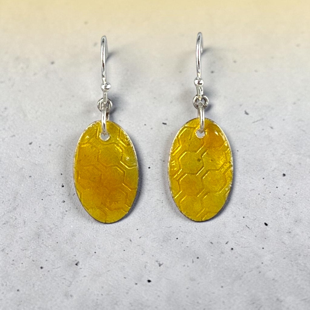 Bedrock Rose oval dangle earrings featuring a honeycomb textured fine silver base with transparent amber glass enamel.