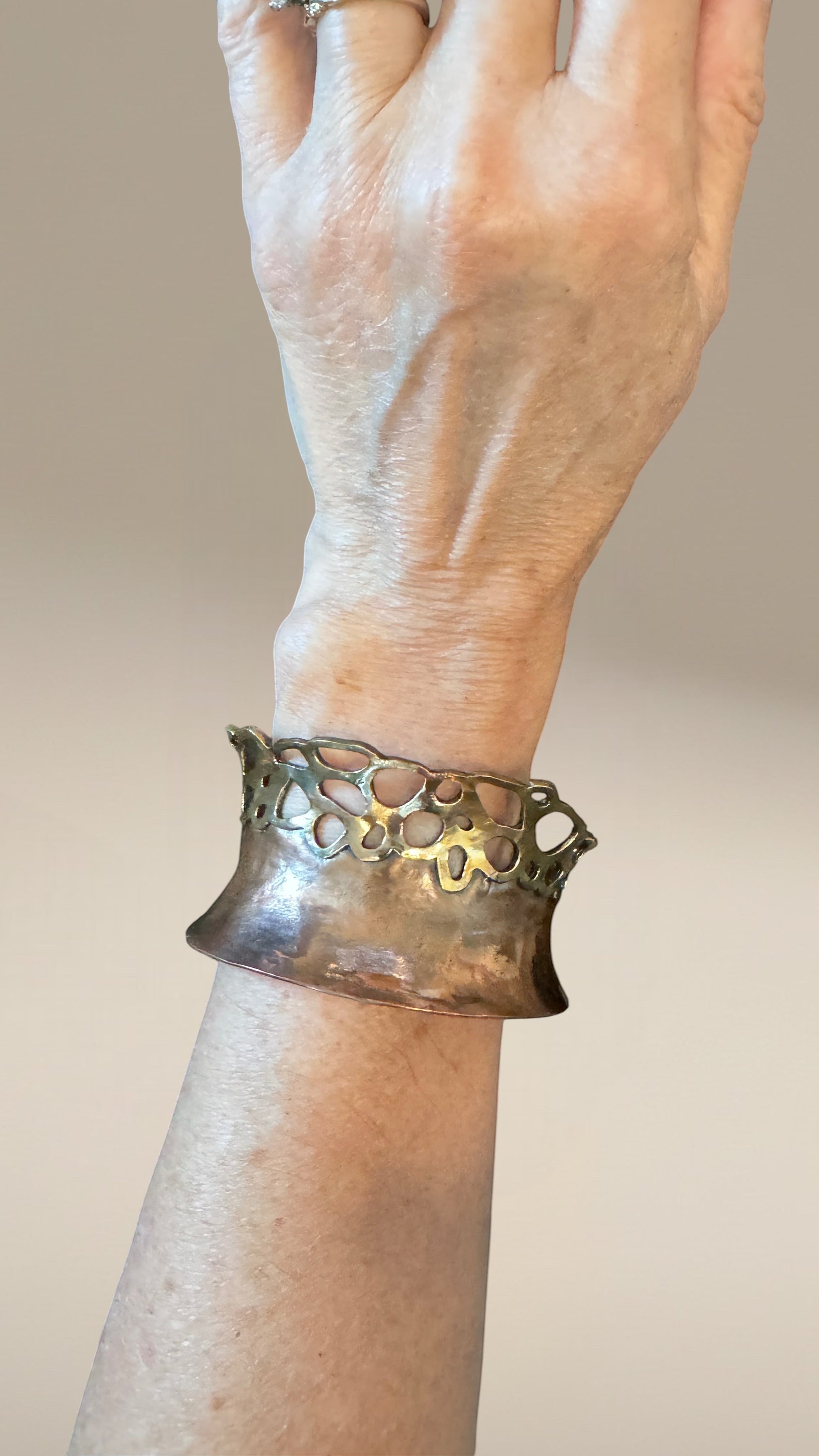 Bedrock Rose lacy pierced copper and brass cuff bracelet worn on a wrist