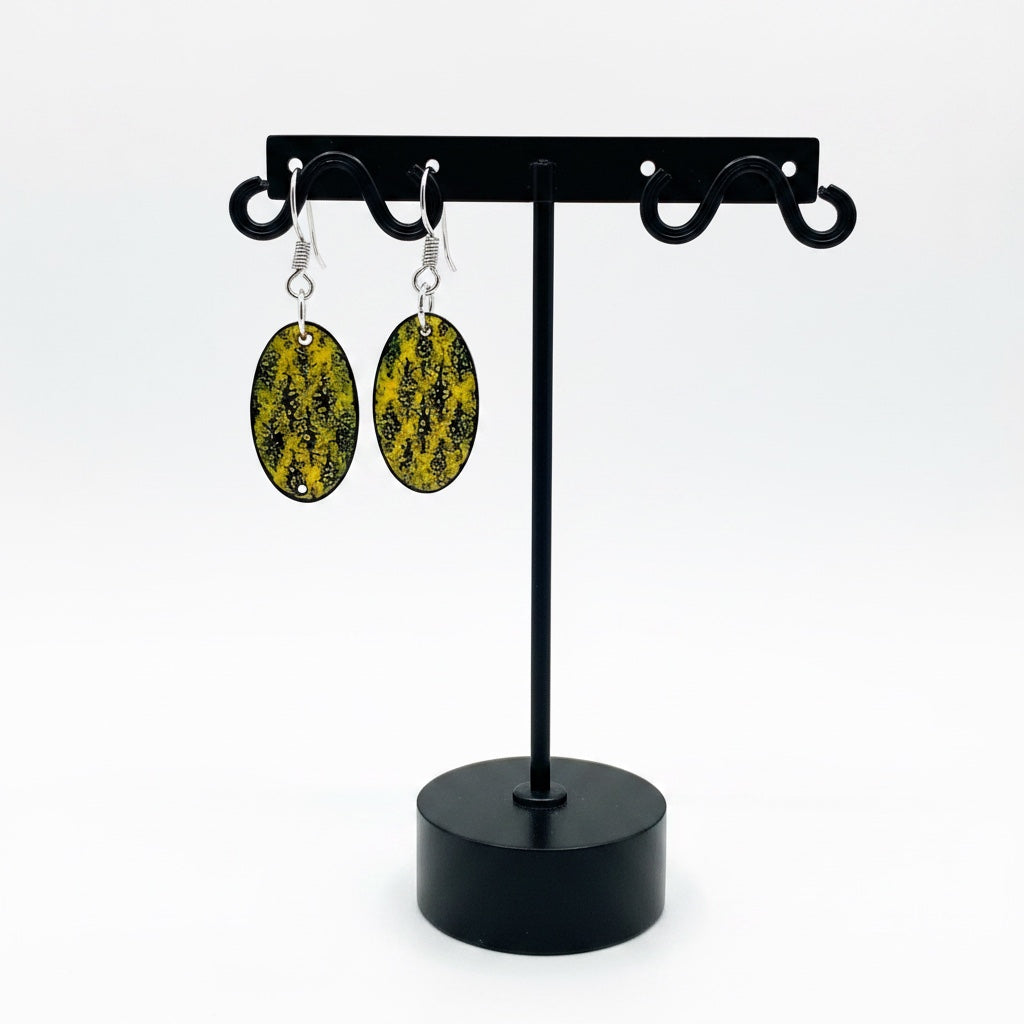 Bedrock Rose oval earrings featuring golden-yellow vitreous enamel with a black stenciled lichen-inspired pattern.