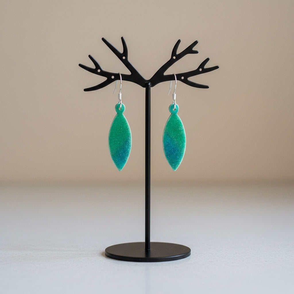 Bedrock Rose marquise earrings in navy blue and lime green enamel with shimmering silver mica on a display stand.