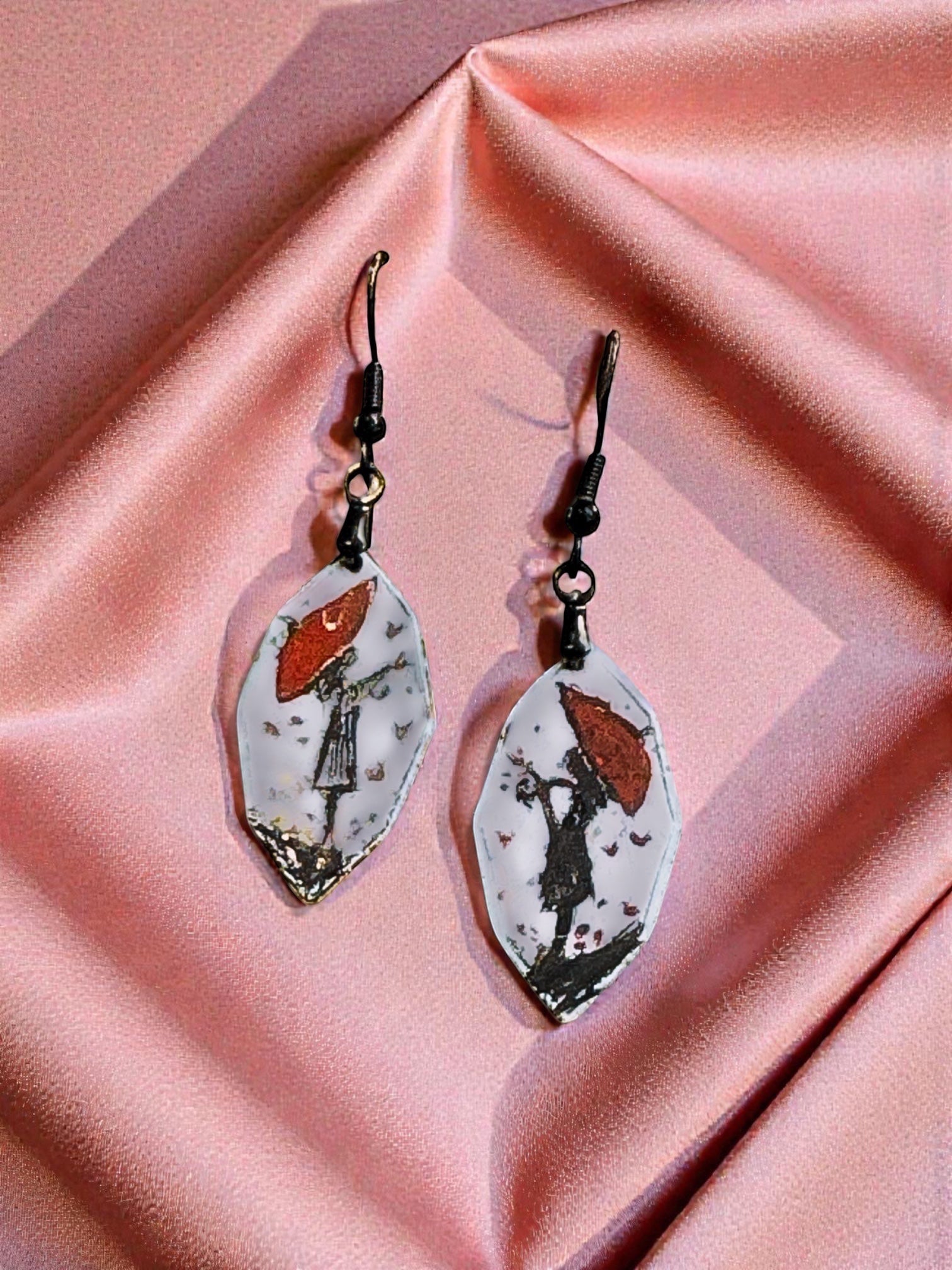 Bedrock Rose artisan shield earrings with hand-painted red umbrella and silhouette on white enamel.
