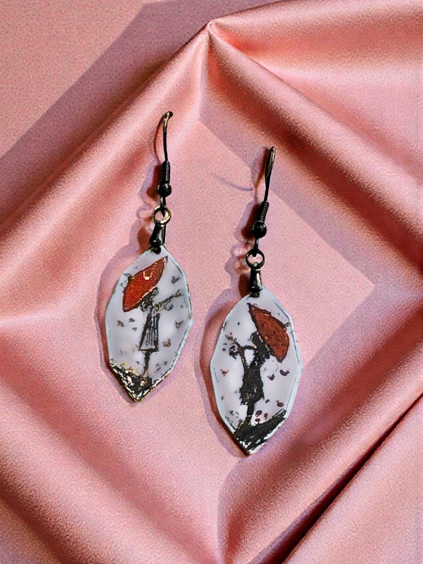 Bedrock Rose artisan shield earrings with hand-painted red umbrella and silhouette on white enamel.