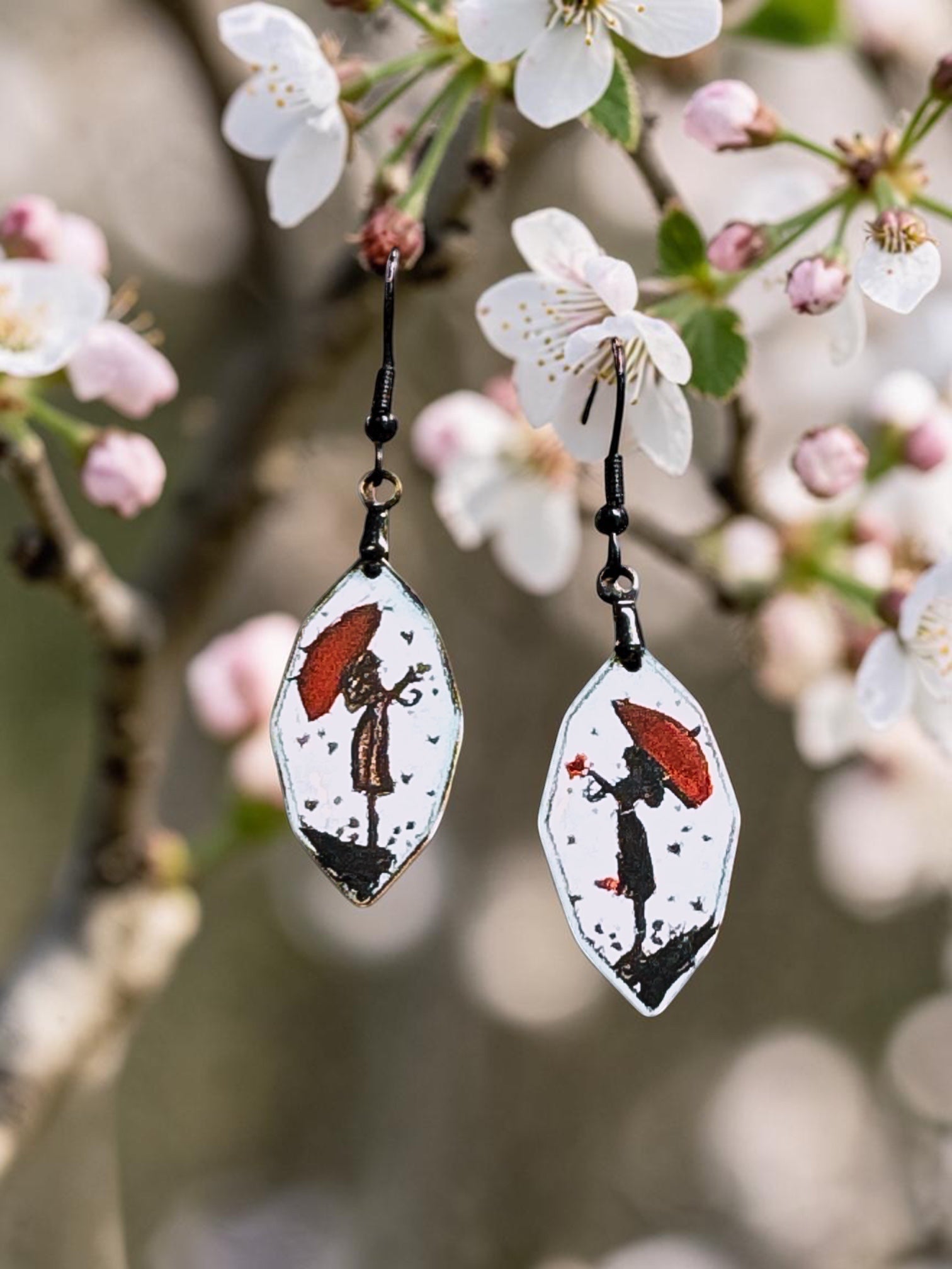 Bedrock Rose artisan shield earrings featuring hand-painted red umbrellas and silhouettes on white enamel.