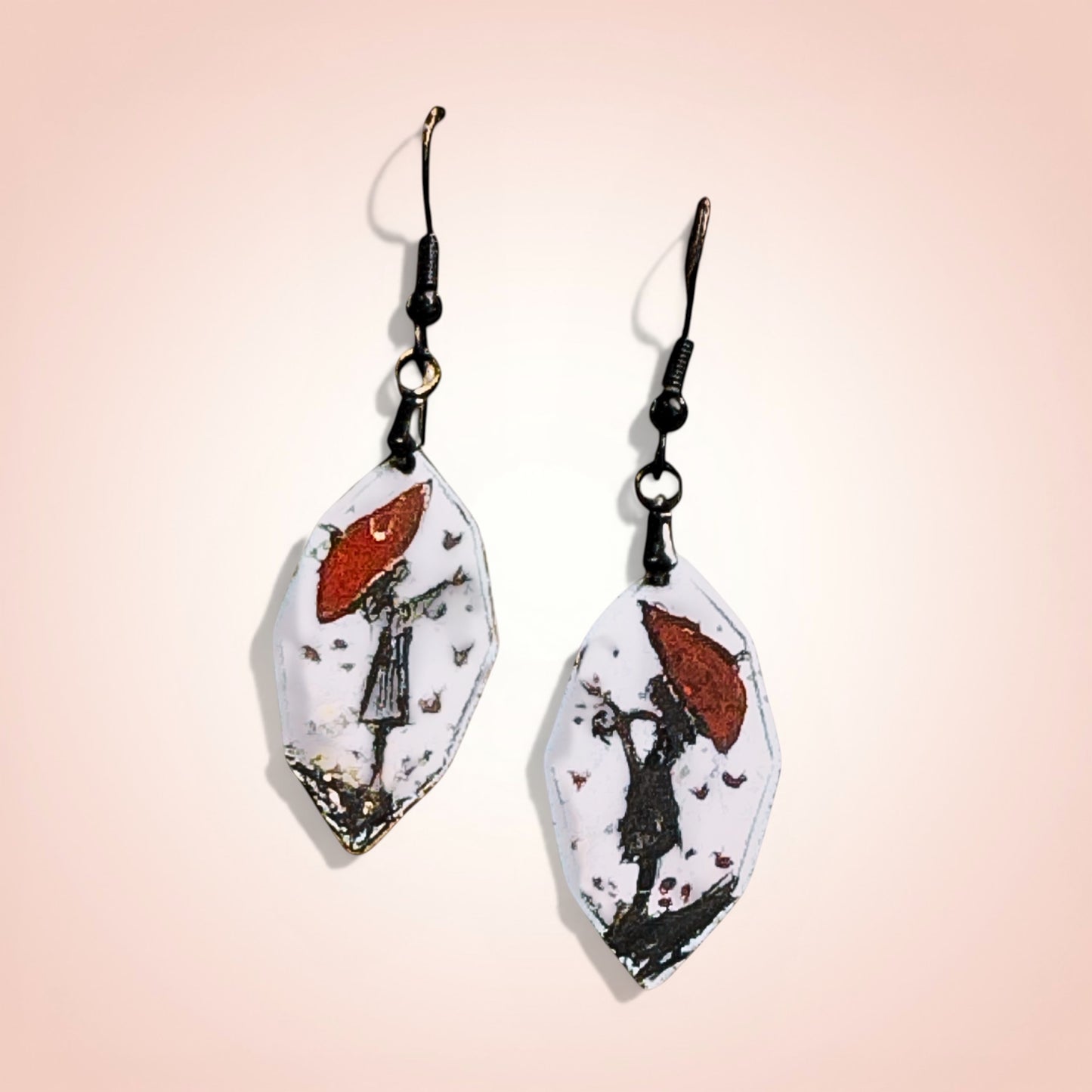 Bedrock Rose artisan shield earrings with hand-painted red umbrella and silhouette design on white enamel.