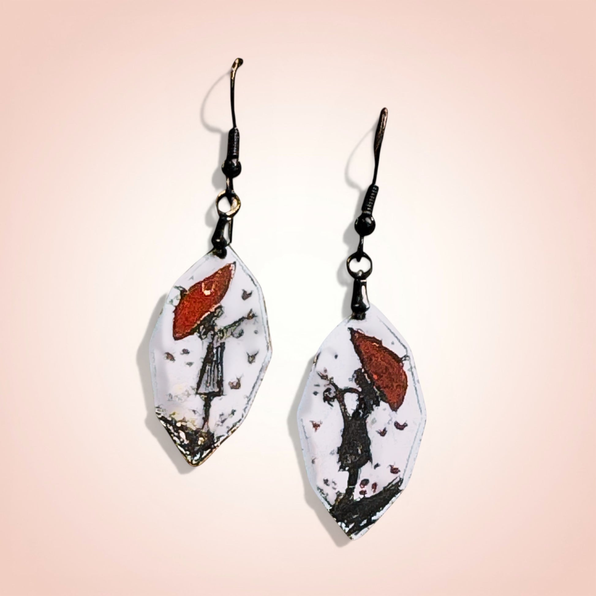 Bedrock Rose artisan shield earrings with hand-painted red umbrella and silhouette design on white enamel.
