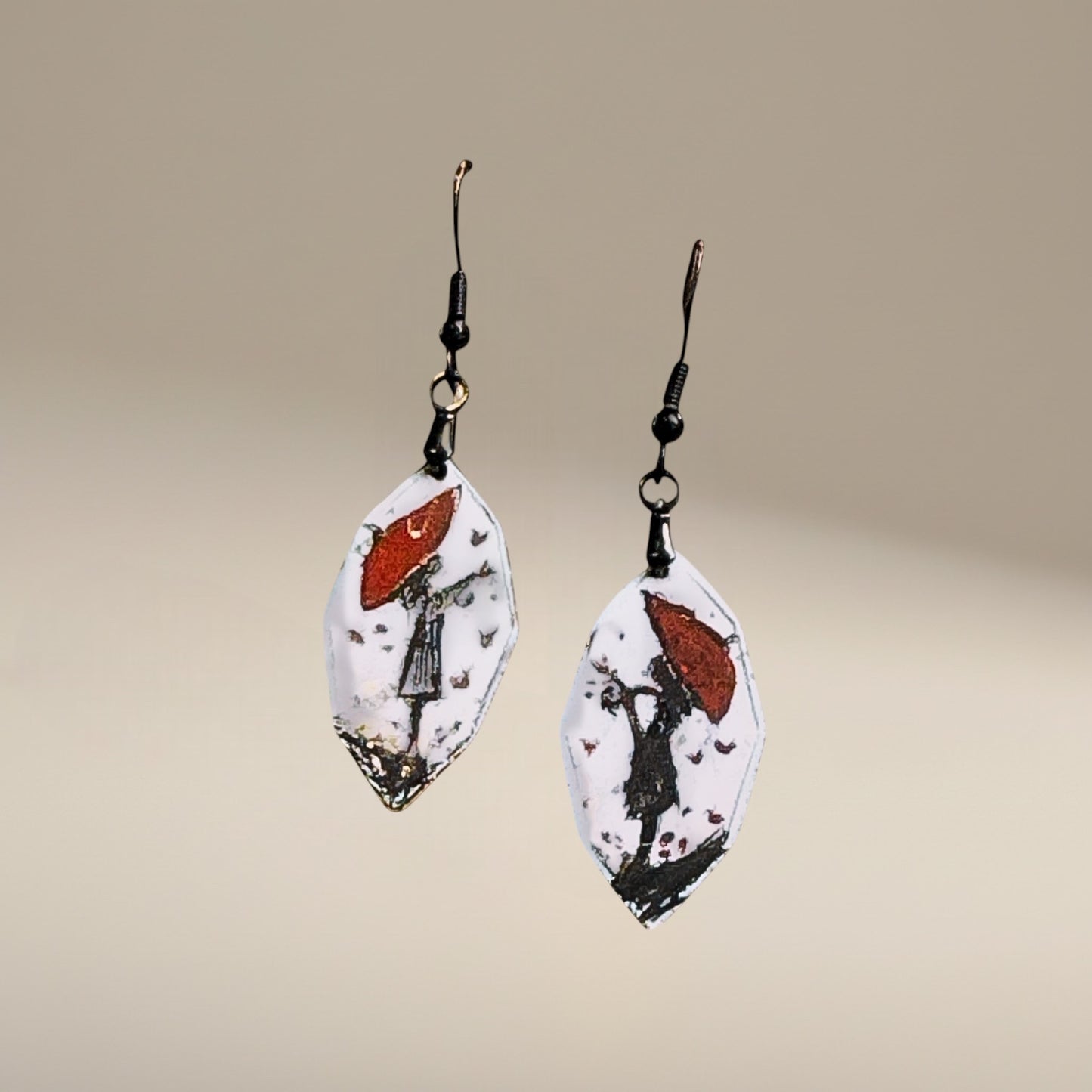 Bedrock Rose artisan shield earrings with hand-painted red umbrella and silhouette design on white enamel.