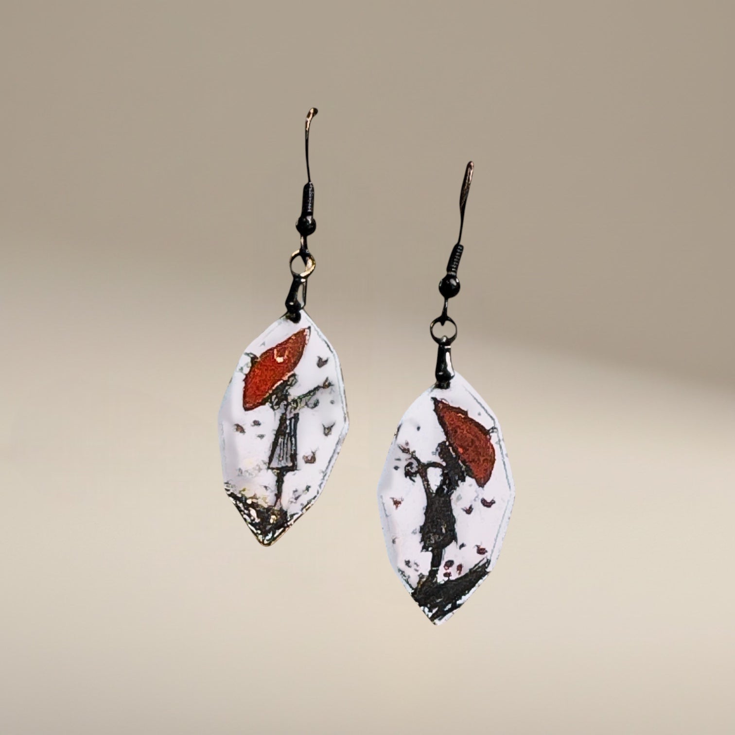 Bedrock Rose artisan shield earrings with hand-painted red umbrella and silhouette design on white enamel.