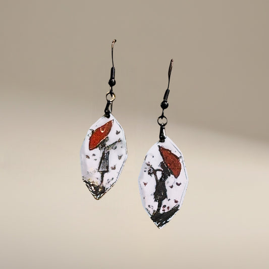 Bedrock Rose artisan shield earrings with hand-painted red umbrella and silhouette design on white enamel.