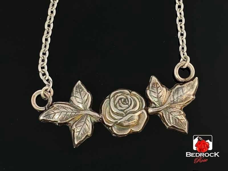 Bedrock Rose sterling silver necklace with rosebud and leaf pendant. Delicate nature-inspired design.