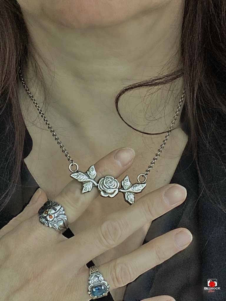 Bedrock Rose sterling silver necklace with rosebud and leaf pendant. Delicate, nature-inspired design.