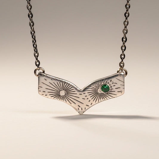 Bedrock Rose silver chevron necklace with radiating line pattern and emerald-nanogem accent.