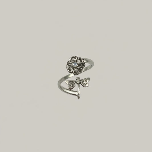 Bedrock Rose sterling silver wraparound ring with a dragonfly on a flower, featuring intricate detailing and a small moonstone accent.