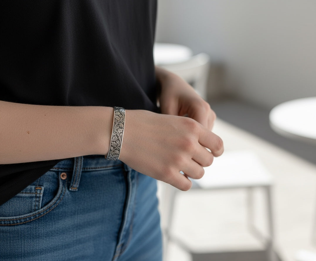 Bedrock Rose silver-plated cuff bracelet with intricate vintage floral vine pattern worn on a woman's wrist