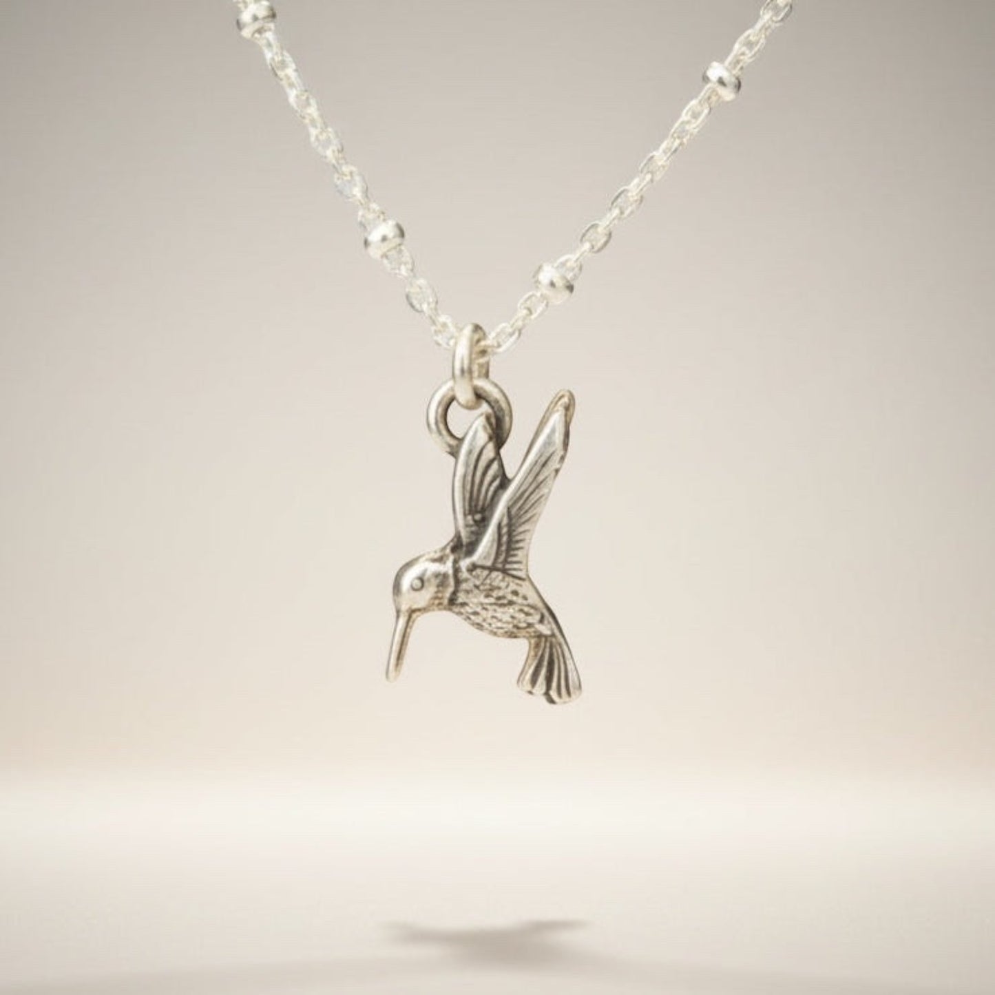 Bedrock Rose sterling silver hummingbird necklace with a delicate satellite chain. Whimsical bird pendant.
