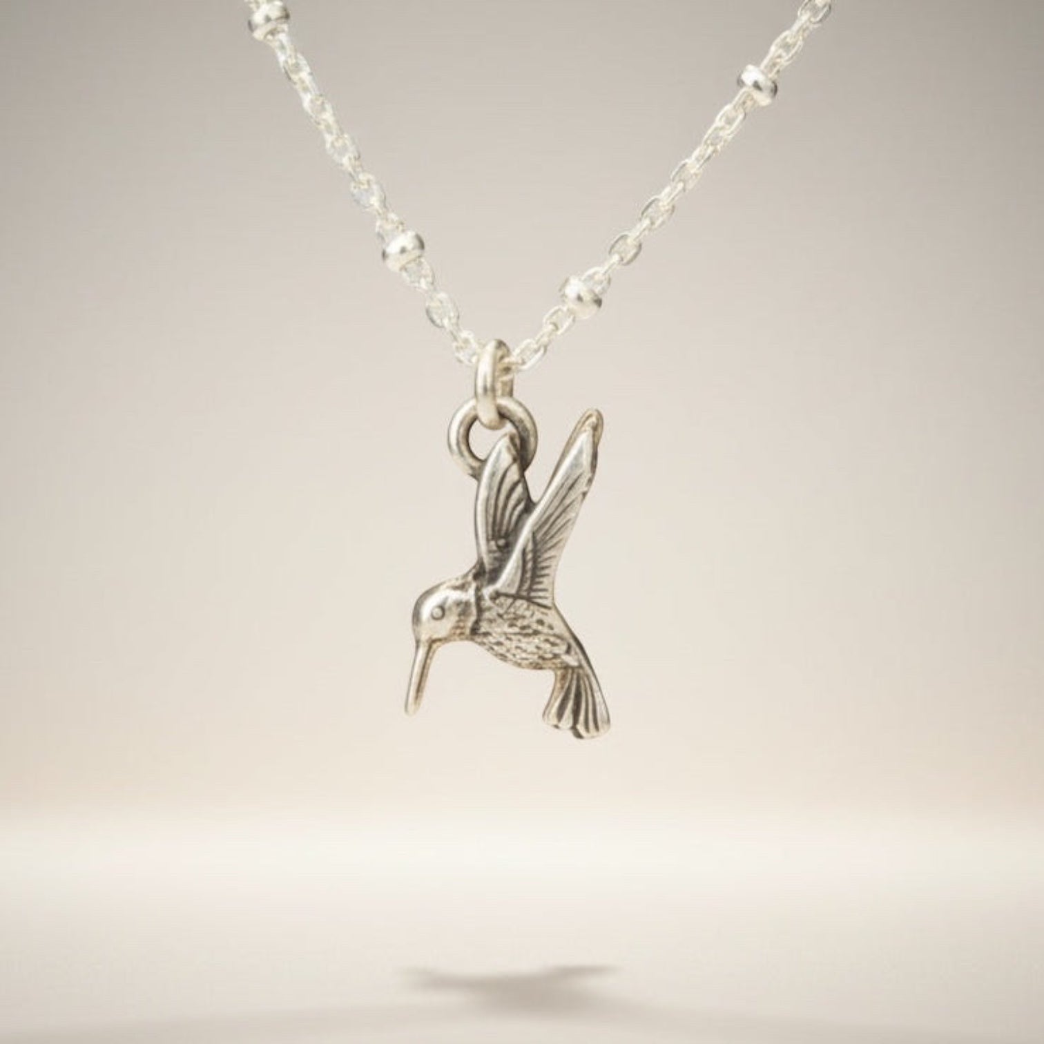 Bedrock Rose sterling silver hummingbird necklace with a delicate satellite chain. Whimsical bird pendant.