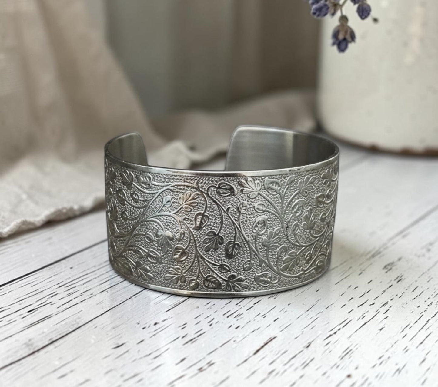 Bedrock Rose silver wide cuff bracelet featuring an intricate embossed leafy vine pattern on a polished metal surface.