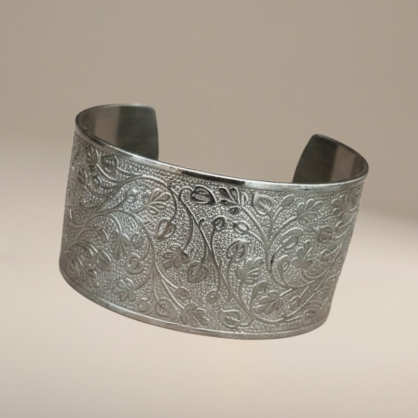 Bedrock Rose silver wide cuff bracelet featuring an intricate embossed leafy vine pattern on a neutral background.