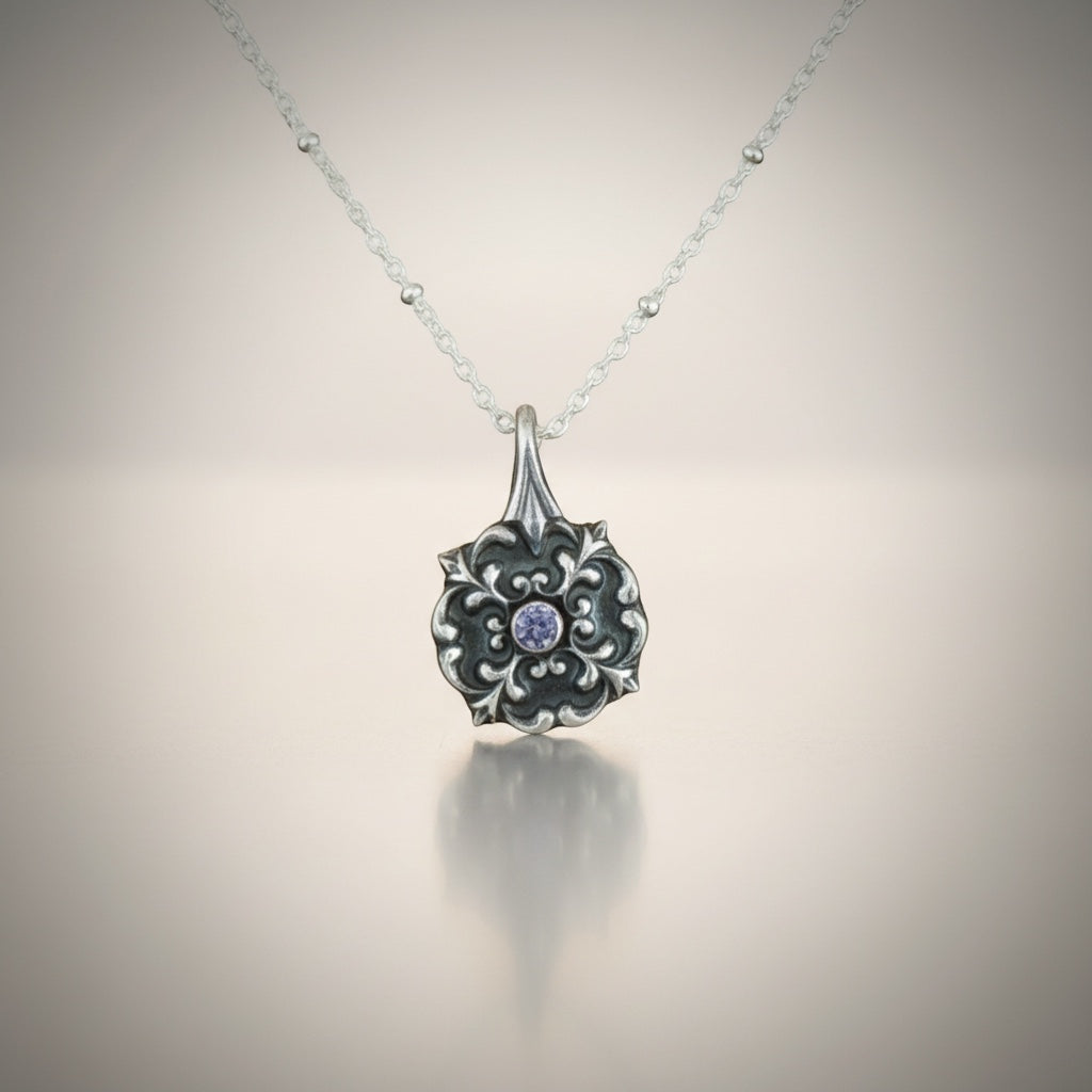 Bedrock Rose petite silver flourish pendant with a central round simulated tanzanite on a fine sterling silver satellite chain.