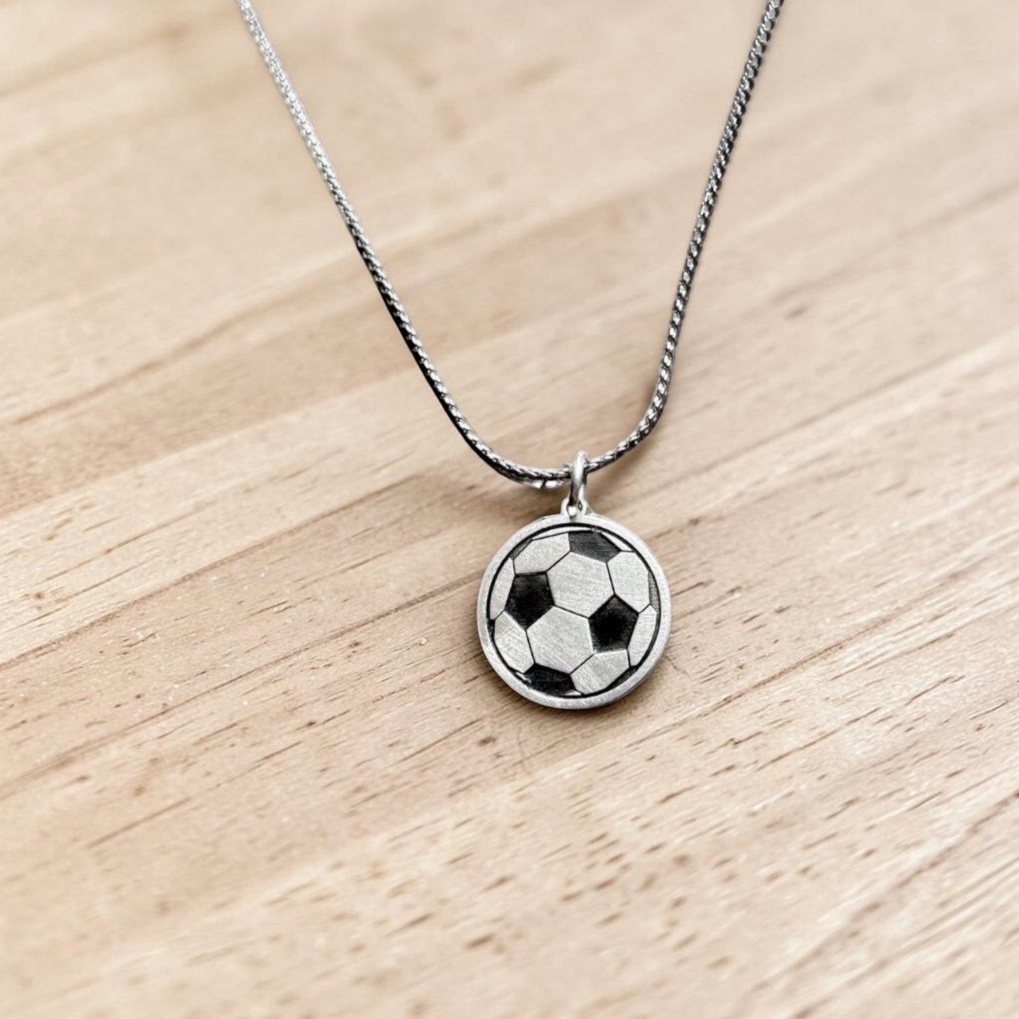Bedrock Rose sterling silver soccer ball pendant necklace with laser-engraved details on a stainless steel chain.