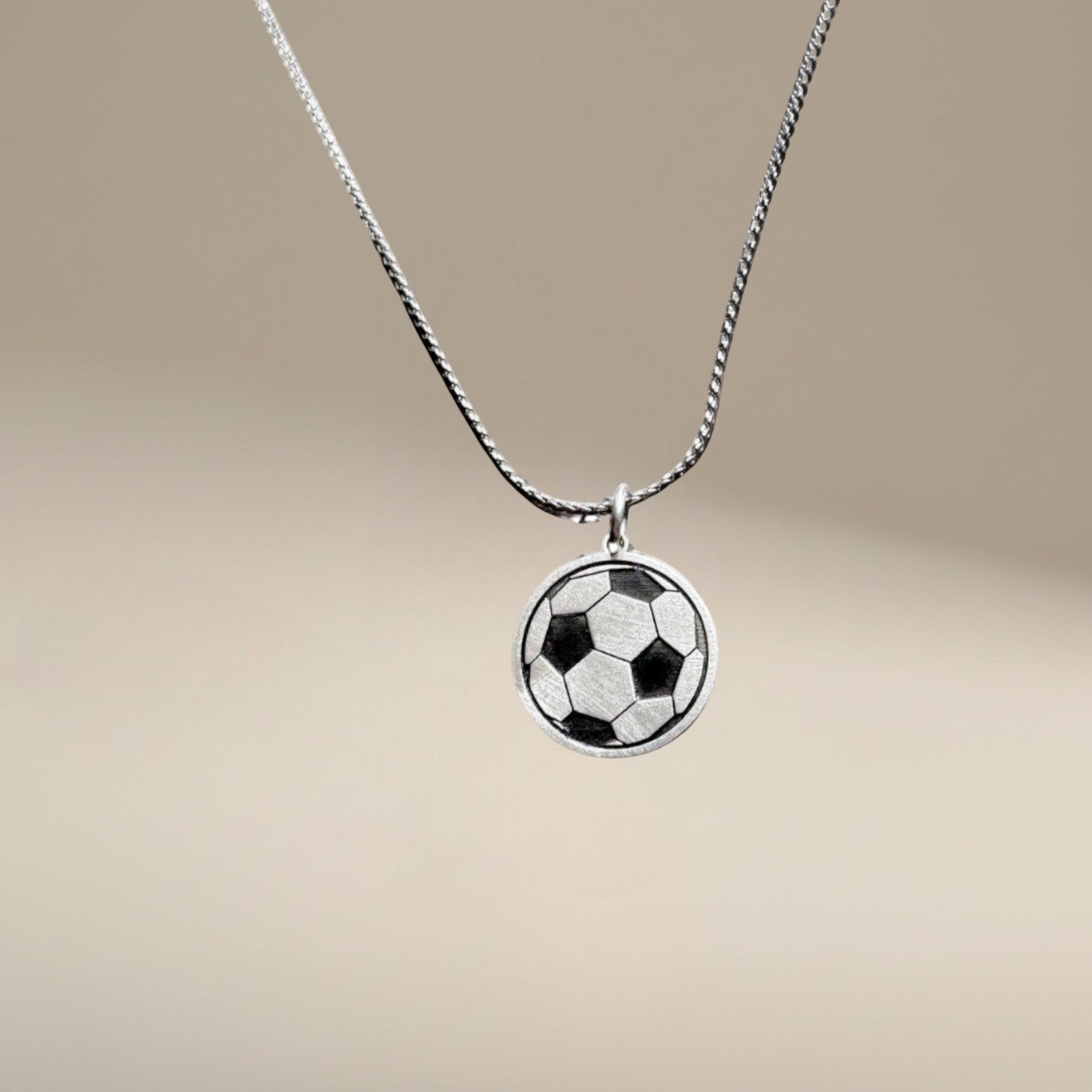 Bedrock Rose sterling silver soccer ball pendant necklace with laser-engraved panel details on a stainless steel chain.