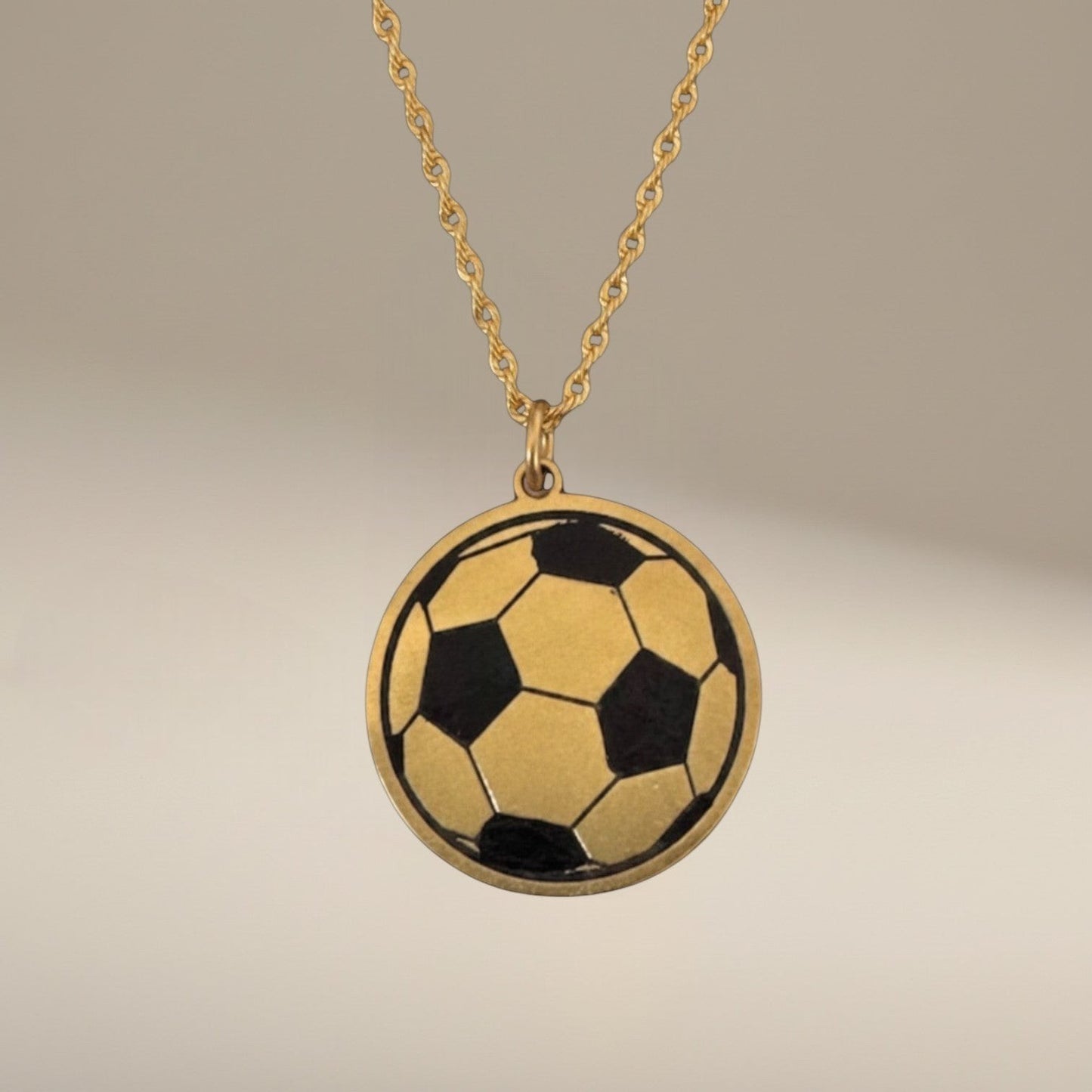 Bedrock Rose brass soccer ball pendant necklace with laser-engraved details on a gold-tone chain.