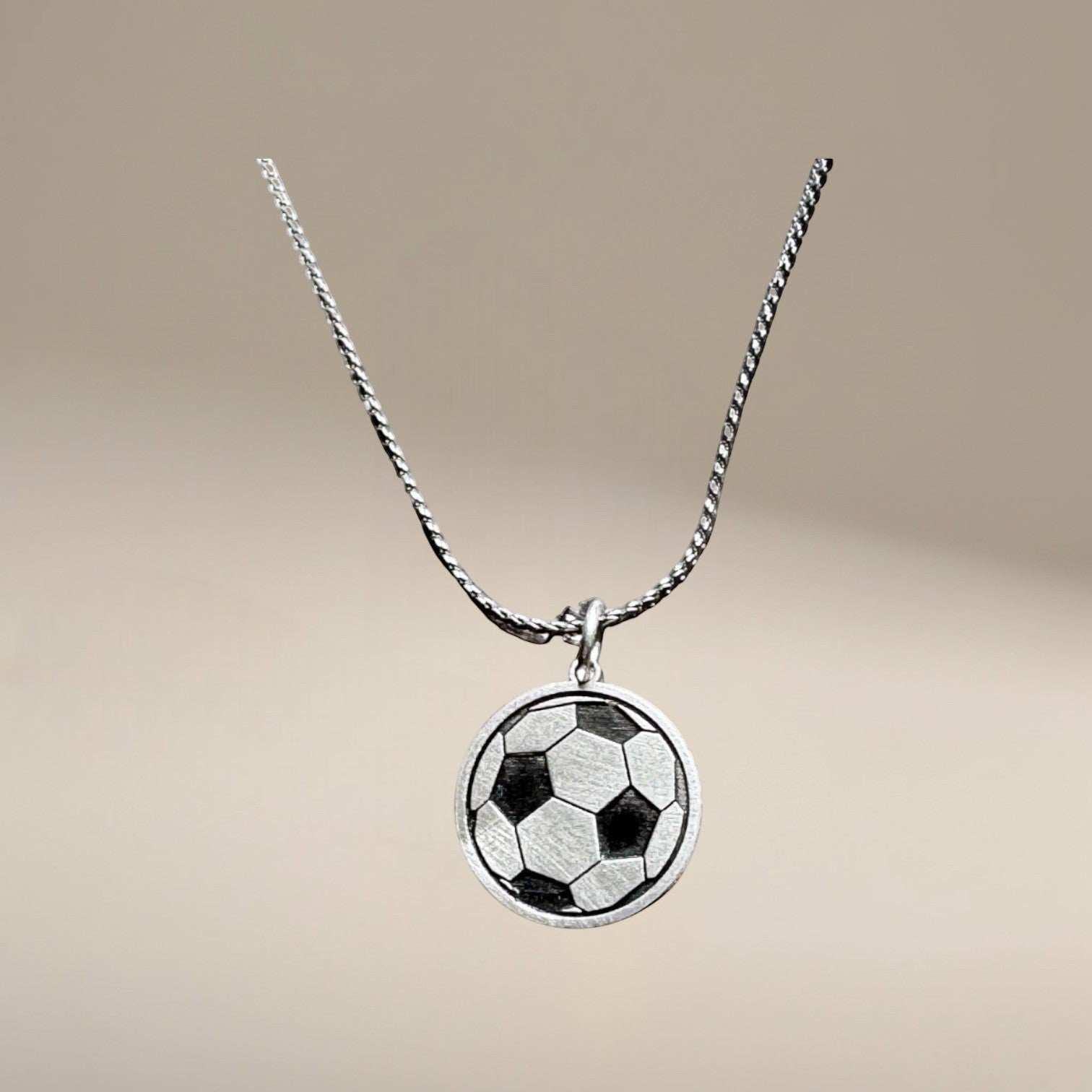 Bedrock Rose sterling silver soccer ball pendant necklace with laser-engraved details on a stainless steel chain.