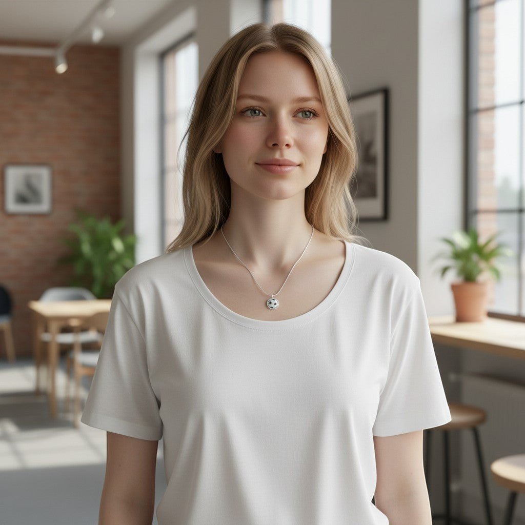 A blonde woman wearing a Bedrock Rose laser-engraved sterling silver soccer ball pendant necklace on a simple chain.