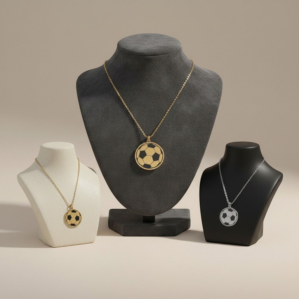 Bedrock Rose laser-engraved soccer ball pendant necklaces in brass and sterling silver on display stands.