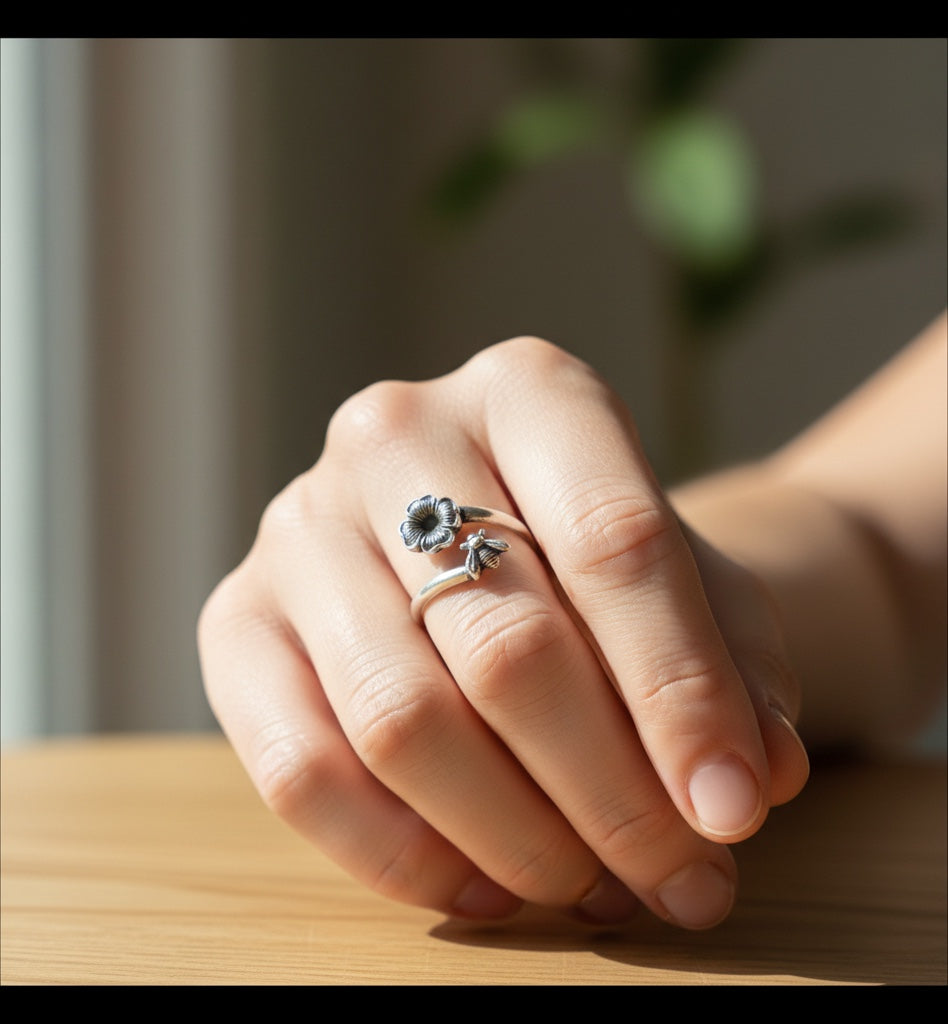 Bedrock Rose sterling silver wrap ring featuring a detailed honeybee and blossom with an oxidized patina on a hand.
