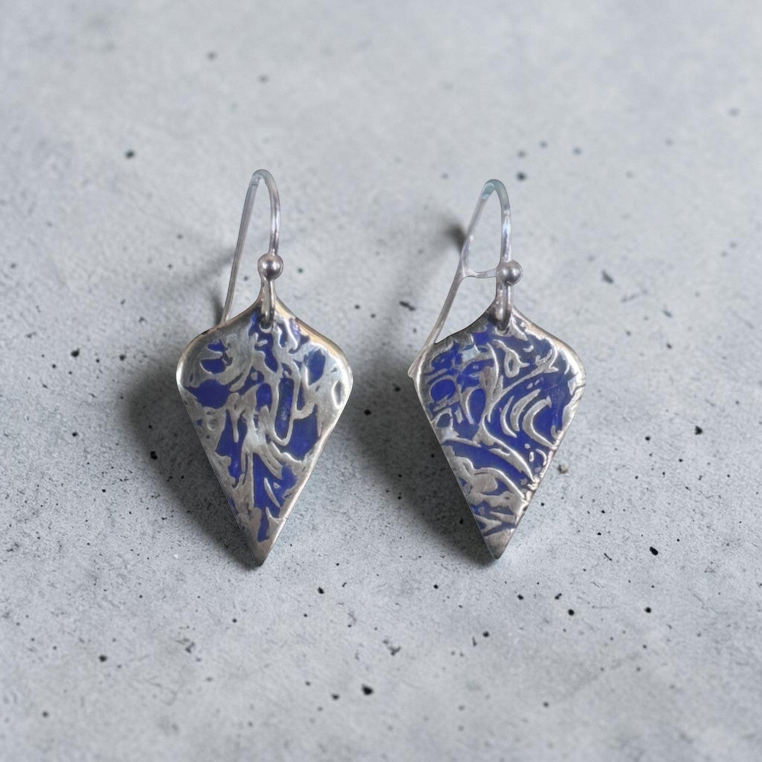 Bedrock Rose sterling silver shield-shaped dangle earrings with blue abstract branch texture and patina finish.