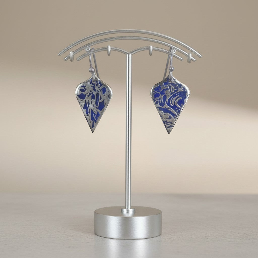 Bedrock Rose sterling silver shield dangle earrings with blue abstract branch texture and patina on a display stand.