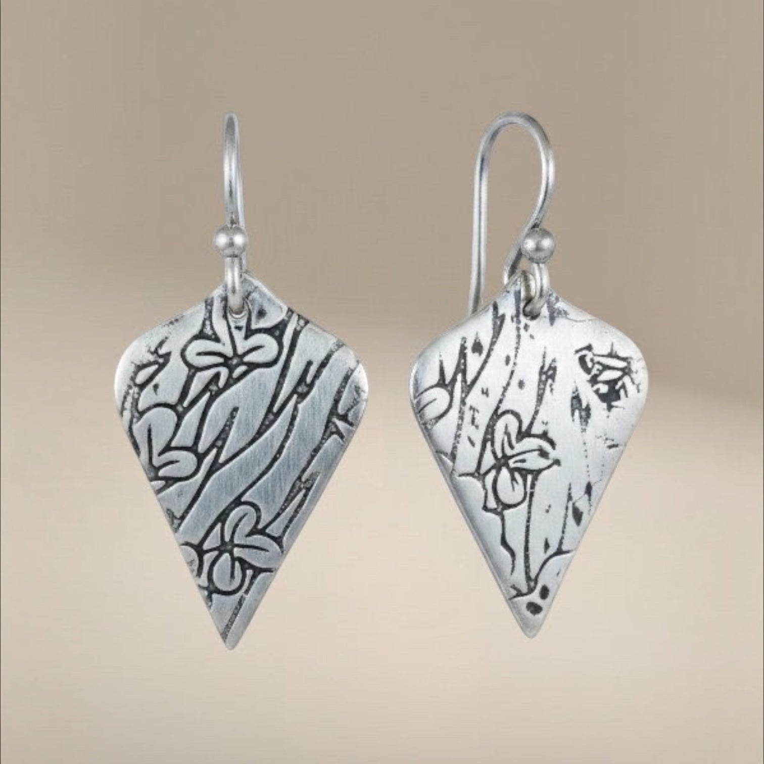 Bedrock Rose sterling silver shield-shaped dangle earrings with oxidized botanical texture and floral details.