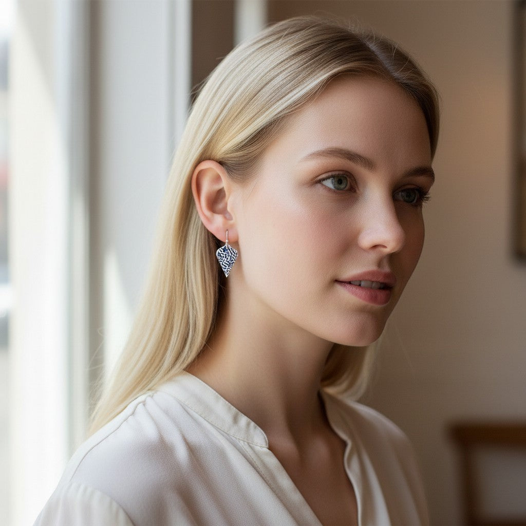 Model wearing Bedrock Rose sterling silver shield dangle earrings with blue coral-inspired textured patina finish.