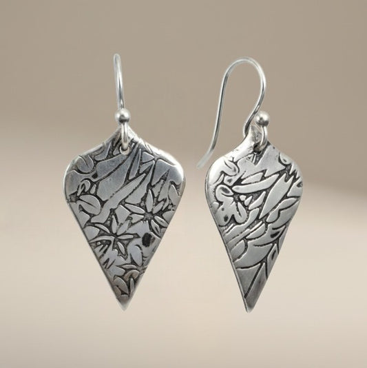 Bedrock Rose sterling silver shield dangle earrings with oxidized floral vine texture and botanical illustration style.