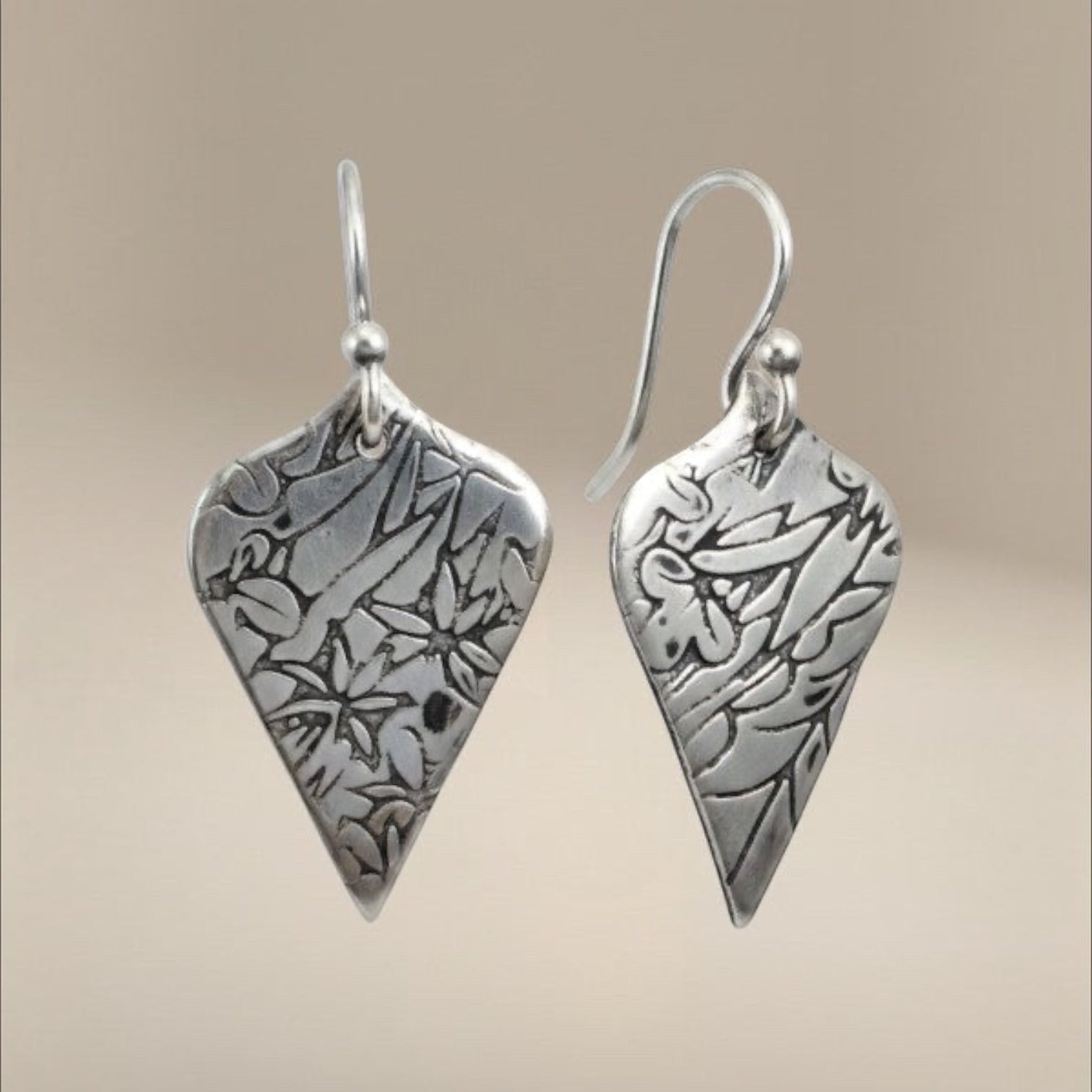 Bedrock Rose sterling silver shield dangle earrings with oxidized floral vine texture and botanical illustration style.