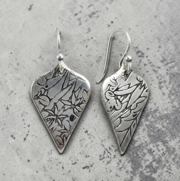 Bedrock Rose sterling silver shield dangle earrings with oxidized floral vine texture and botanical illustration style.