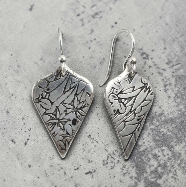 Bedrock Rose sterling silver shield dangle earrings with oxidized floral vine texture and botanical illustration style.