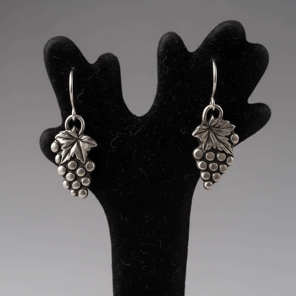 Bedrock Rose sterling silver grape cluster dangle earrings with detailed leaf accents on a black display stand.