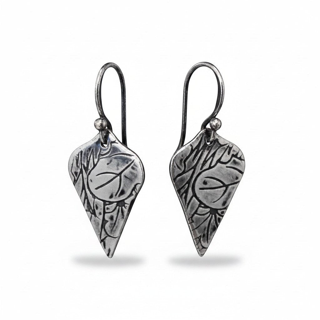 Bedrock Rose sterling silver shield-shaped dangle earrings with oxidized lotus texture and radiating line details.