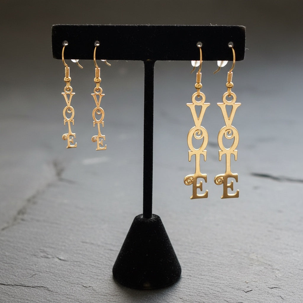 Bedrock Rose gold-tone dangle earrings with "VOTE" script and decorative scrolls. Laser-cut statement jewelry.