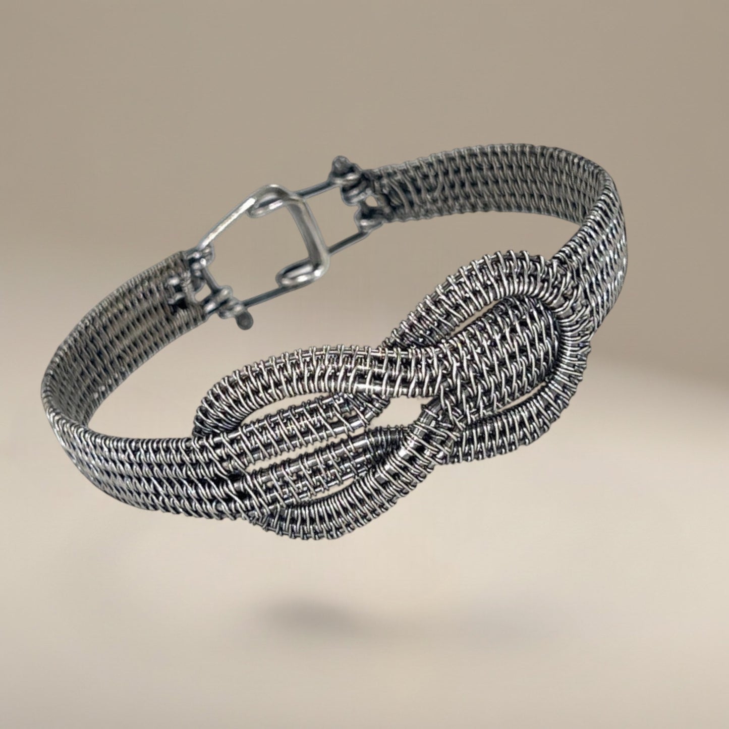 Bedrock Rose woven sterling silver infinity bracelet with a secure clasp, featuring an intricate wire-wrapped design.
