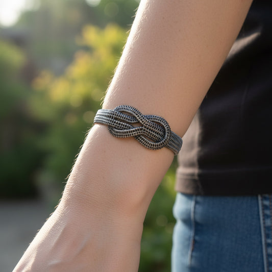 Bedrock Rose woven sterling silver infinity bracelet worn on a wrist, featuring a detailed eternal love knot design.